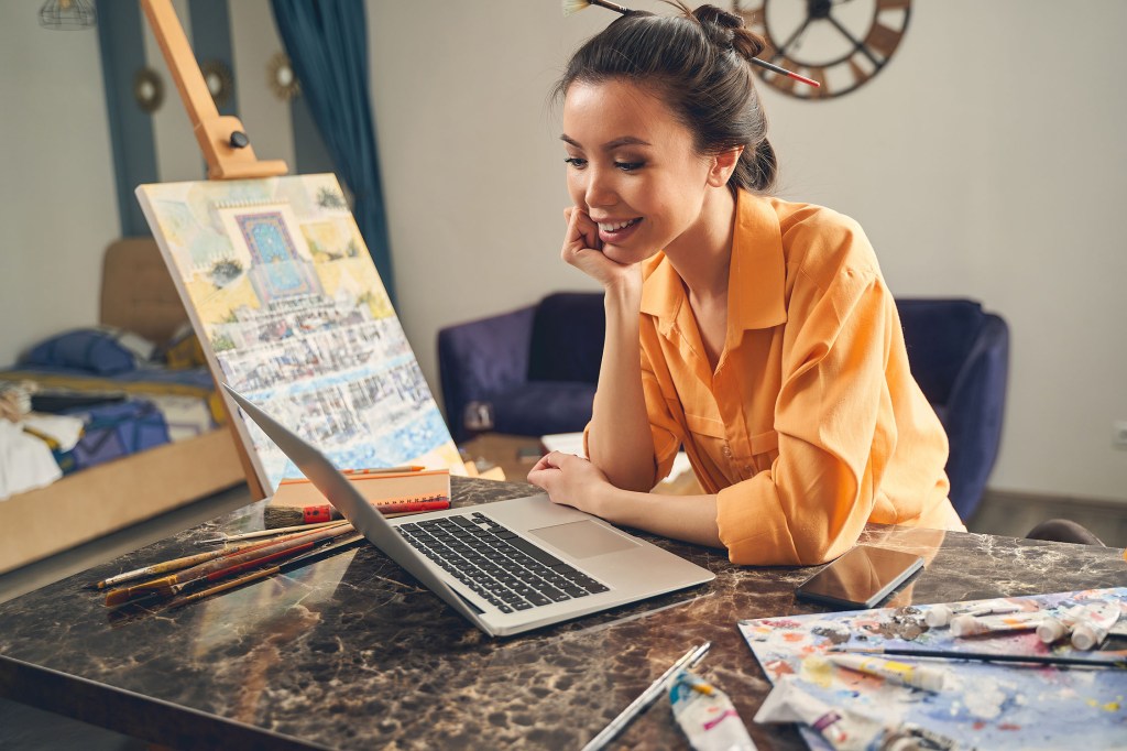 Artist talking to another artist via laptop during online art exhibition