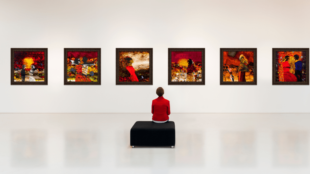 Packing work for art shows, art exhibition with red paintings and woman in red top admiring work.