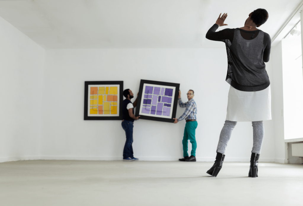 hanging an art exhibition, curator and hanging team with two pictures 