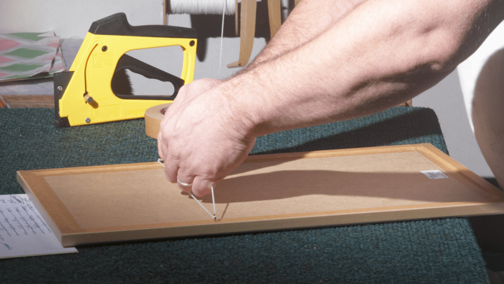 Framer putting back onto frame to photograph glazed artworks remove the backing boards and artwork, take out the glass a reframe unglazed for the shots.