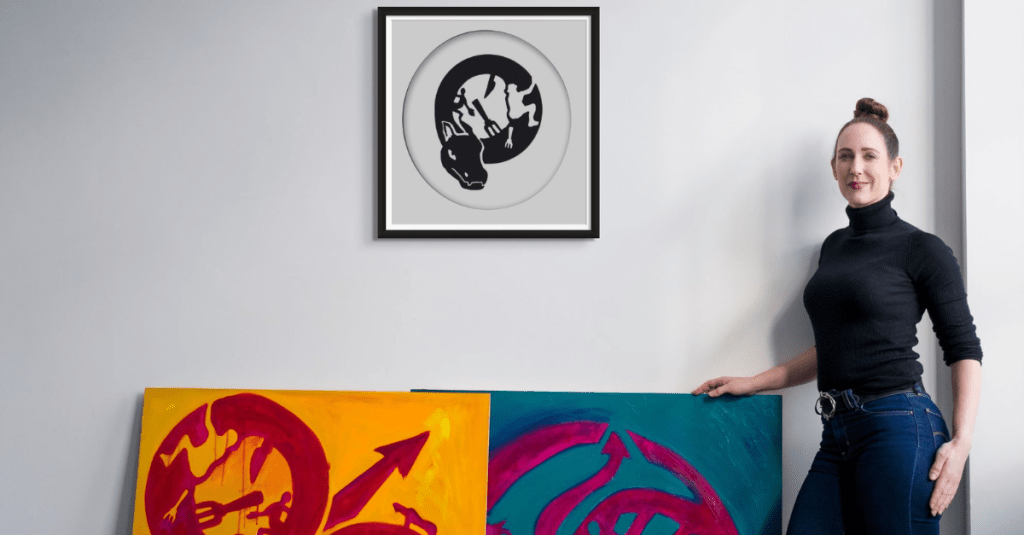 Charlie Kirkham artist next to oil paintings and laser cut dragon art 