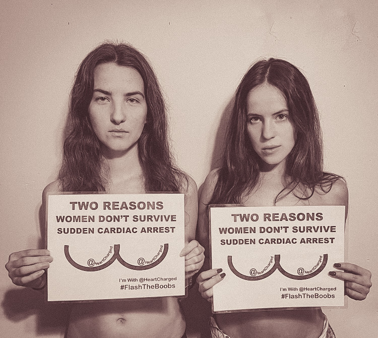 Hannah and Bethany Keime, HeartCharged showing the flash the boobs posters in a mug shot style photo
